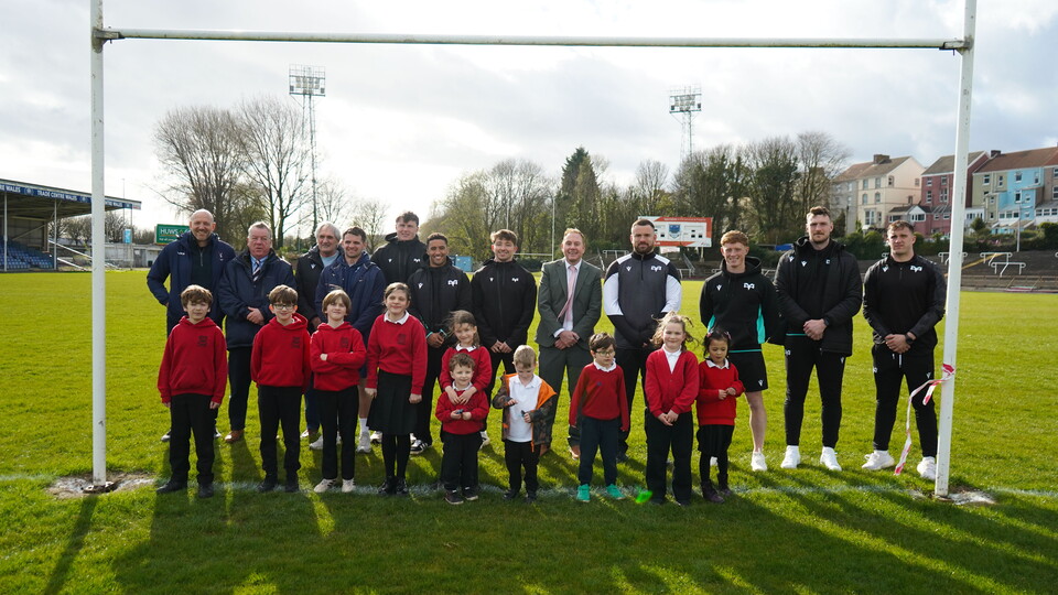 Ospreys, the council and community members pose for a photo under the posts at St Helens 