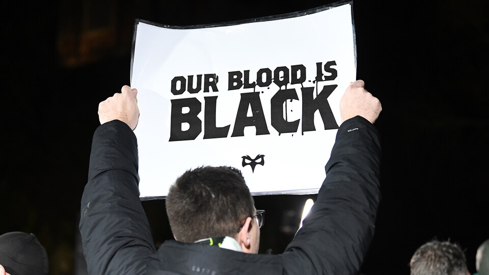 An Ospreys supporter holds up an 'Our Blood is Black' sign
